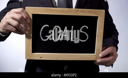 Ziele auf Tafel geschrieben: "Der Mensch in der klassischen Anzug Holding unterzeichnen, Business Konzept Stockfoto