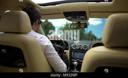 Geschäftsmann Autofahren und am Telefon sprechen über Wireless Headset, Technologie Stockfoto