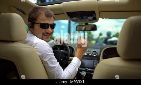 Glückliche Menschen in Sonnenbrille fahren Auto auf Urlaub, Zeige Thumbs-up Hand Geste Stockfoto