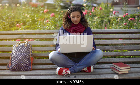 Pretty Woman in Kopfhörer genießen Sie Ihre Lieblingsmusik auf der Bank draußen Inspiration Stockfoto