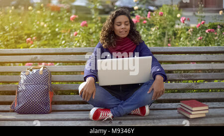 Biracial Student in gute Laune sitzt auf der Bank, Träumen über die Zukunft Stockfoto