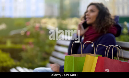 Nahaufnahme der Einkäufe, lady Gespräche über Telefon auf Hintergrund, rühmt sich über Verkäufe Stockfoto