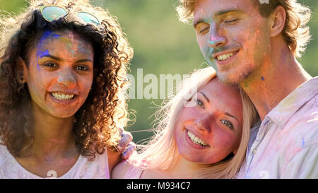 Positive Emotionen von glücklichen männlichen und weiblichen Freunde umarmen im Color Festival Stockfoto