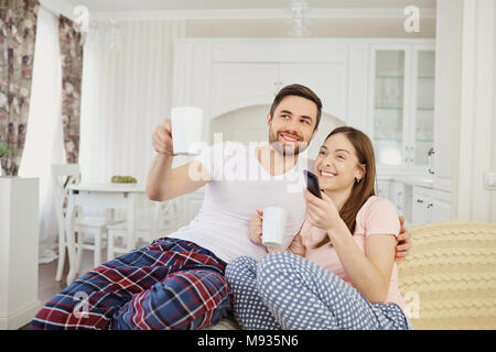 Ein Mädchen und ein Kerl Fernsehen sitzen auf dem Sofa im Zimmer. Stockfoto