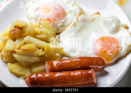 Zwei Eier mit Bratkartoffeln und Würstchen auf Platte Stockfoto