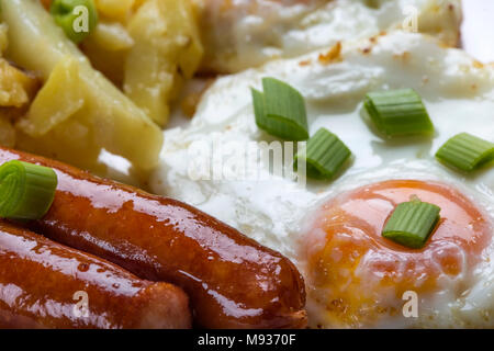 Nahaufnahme der Eier mit Bratkartoffeln und Würstchen mit Stücken von grüne Zwiebel Stockfoto