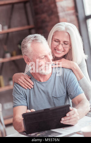 Schöner alter Mann sitzen und die Verwendung des Tablet. Stockfoto