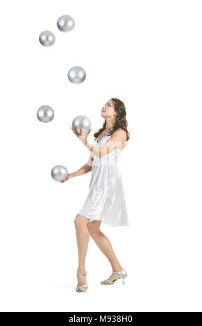 Eine junge weibliche circus Performer, jongliert Silber Kugeln. Studio shot auf weißem Hintergrund, isolierte Bild. Stockfoto