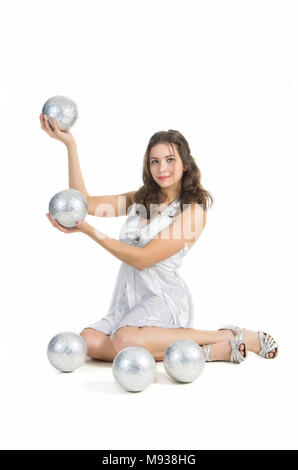 Eine junge weibliche circus Performer, jongliert Silber Kugeln. Studio shot auf weißem Hintergrund, isolierte Bild. Stockfoto