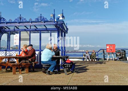 Ältere Menschen genießen Sie die Frühlingssonne sitzen auf der Pier von Eastbourne, East Sussex England Großbritannien Stockfoto
