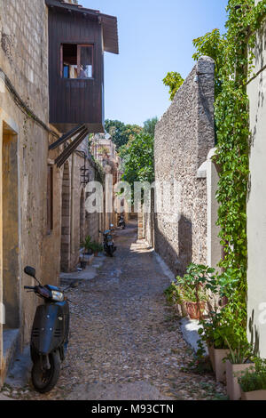 Schmale Straße mit Balkon und Motorroller in der Altstadt von Rhodos, Griechenland, 11. August 2017 Stockfoto