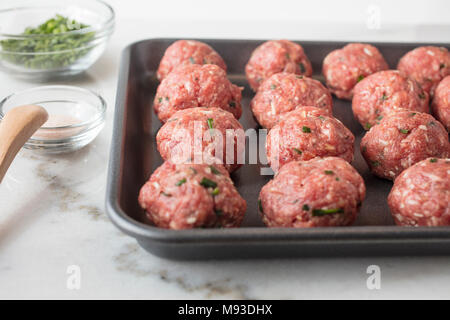 Rohes Fleisch Kugeln vorbereitet und bereit gebacken auf ein Blatt zu sein pan mit Gewürzen auf der Seite Stockfoto