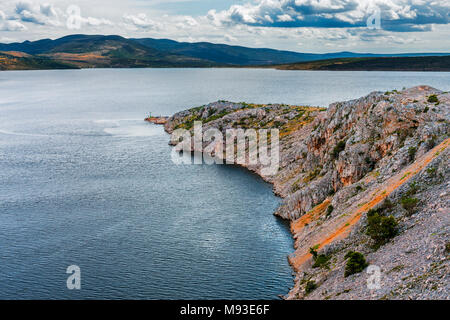 Maslenica der Meerenge Novsko Zdrilo Einlass in Kroatien, in der Nähe von Zadar, mit atmosphärischen Cumuluswolken und beschattet die Berge in der Ferne und kleinen Pier Stockfoto