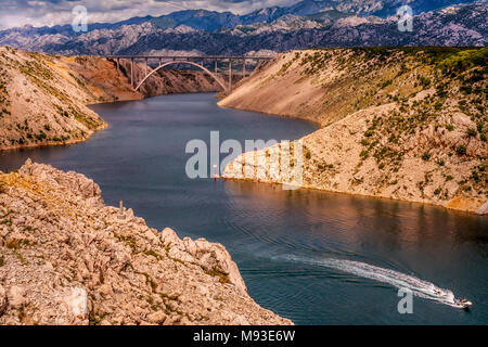 Maslenica meer Autobahnbrücke in Kroatien auf der Autobahn A1, die die Meerenge Novsko Zdrilo mit einem einsamen Speedboot und flankiert von Velebit Stockfoto