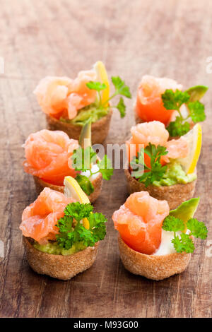 Croustades knuspriges Gebäck Fälle mit gesalzenen Lachs und Avocado auf hölzernen Tisch gefüllt Stockfoto