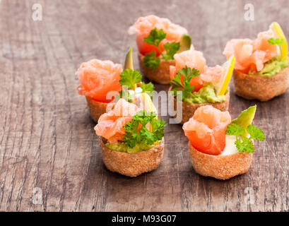 Croustades knuspriges Gebäck Fälle mit gesalzenen Lachs und Avocado auf hölzernen Tisch gefüllt Stockfoto