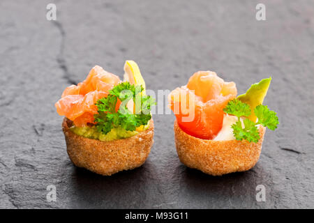 Croustades knuspriges Gebäck Fälle mit gesalzenen Lachs und Avocado auf schwarzen Stein Hintergrund Stockfoto