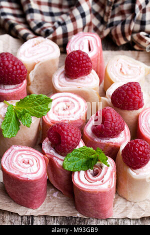 Gerollt Milch und Himbeer Pfannkuchen am Holztisch Stockfoto