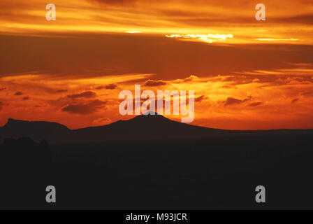 Ein wunderschöner Sonnenuntergang über dem Tafelberg und den umliegenden Gipfeln in Kapstadt, von der anderen Seite der Bucht in Rooi Els, Südafrika. Stockfoto