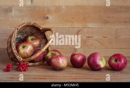Rote Äpfel in einem Korb auf einem hölzernen Hintergrund Stockfoto