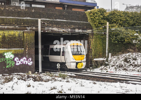 C2C-Bahn Leigh mit Abreise am Meer Station aus Graffiti verziert Brücke während Tier aus dem Osten Wetterphänomen Schnee. Winter Stockfoto