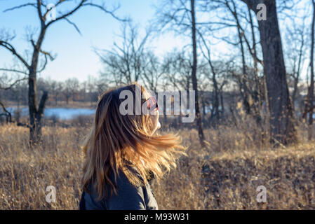 Frau Wandern in Wald mit Wind, blondes Haar im hellen Sonnenlicht am Nachmittag Stockfoto
