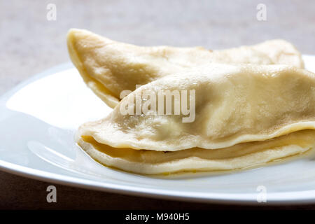 Pierogi, pyrohy oder Teigtaschen, gefüllt mit Fleisch (und Zwiebel oder Pilze), können mit saurer Sahne serviert werden. Stockfoto