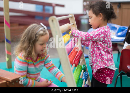 Zwei Mädchen spielen mit einem Abacus in einem Kindergarten in Warwickshire, Großbritannien Stockfoto