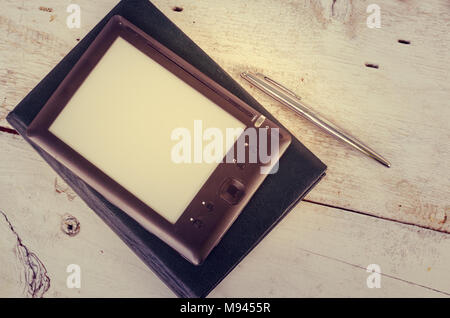 Schwarz ereader mit Notebook in Leder und Kugelschreiber auf Vintage alten rustikalen Holztisch. Leere E-book Reader. Neue Technologien in der Bildung. Zurück Stockfoto