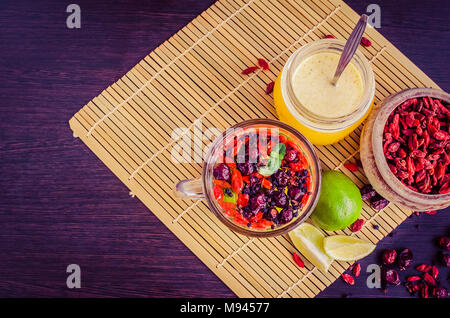 Frische Antioxidans Kräutertee aus getrockneten Goji Beeren, sweetbrier und Heidelbeere in ein Glas Schale auf Holz- Hintergrund mit Limettensaft und Honig. Alternative me Stockfoto