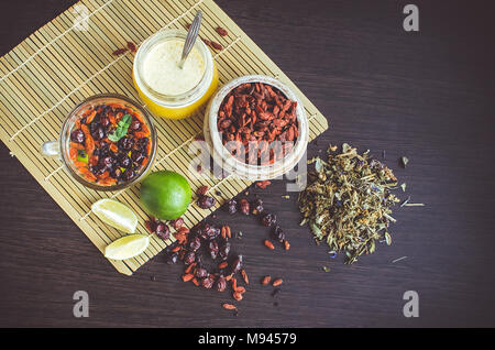 Immer noch leben, Glas Tasse Kräutertee mit Kalk, Honig, Goji Beeren, sweetbrier und Heidelbeeren auf Holz- Hintergrund. Gesundes Essen. Alternative Medizin. Stockfoto