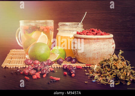 Immer noch leben, Glas Tasse Kräutertee mit Kalk, Honig, Goji Beeren, sweetbrier und Heidelbeeren auf Holz- Hintergrund. Gesundes Essen. Alternative Medizin. Stockfoto