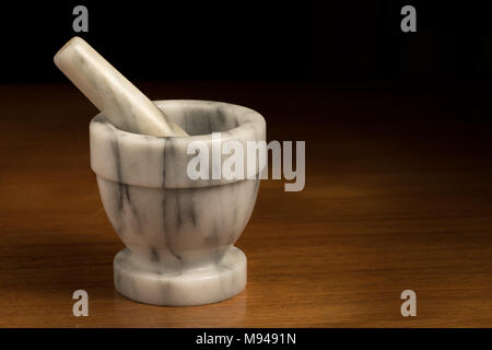 Mörser aus Stein stehend auf einem braunen Holztisch Stockfoto