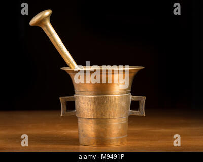 Mörser aus Messing stehend auf einem braunen Holztisch Stockfoto