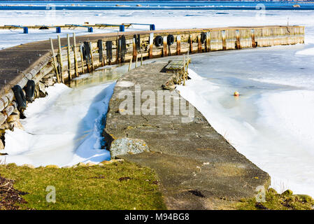 Auftauen Frühling Eis von ein paar Stege. Band des offenen Meer in der Ferne. Schmelzwasser in der Nähe des Bootsanleger. Lage Hasslo Insel im südlichen Schweden. Stockfoto