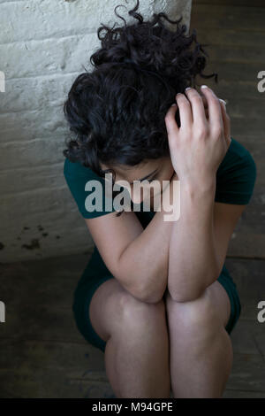 Traurige junge Frau saß auf dem Boden nach unten schauen. Stockfoto