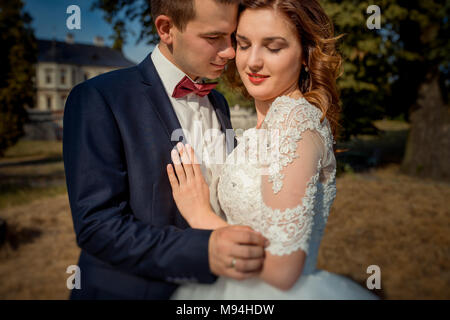 Stilvolle sensible Jungvermählten sind zärtlich umarmen. Die close-up Outdoor Portrait. Stockfoto