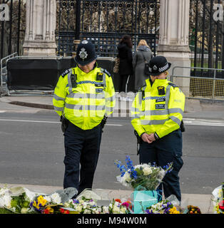 London, Großbritannien. 22. März 2018 Zwei Polizisten an der Blumen außerhalb des House of Commons zum Gedenken an den 1. Jahrestag der Westminster Terroranschlag aussehen. Credit: Ian Davidson/Alamy leben Nachrichten Stockfoto