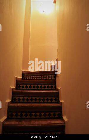 Fliesen Treppen in einem marokkanischen Riad um die Ecke unter der goldenen Glanz einer Wand Licht. Stockfoto