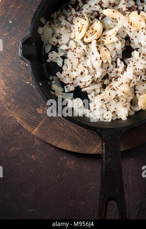 Gebratenen Zwiebeln, Knoblauch und Senf in einer gusseisernen Pfanne freien Speicherplatz. Indisches essen Vertikale Stockfoto