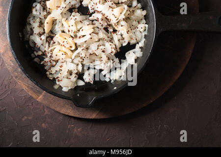Gebratenen Zwiebeln, Knoblauch und Senf in einer gusseisernen Pfanne. Indisches essen horizontal Stockfoto