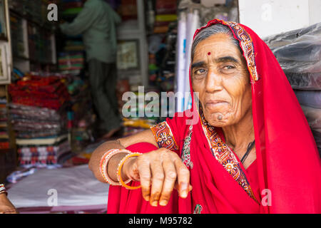 Mandawa, Indien - 24. Februar 2018: Portrait eines älteren indischen Frau mit traditionellen Kleid Saree sitzen Infornt ein Textilgeschäft in Mandawa, Rajas Stockfoto