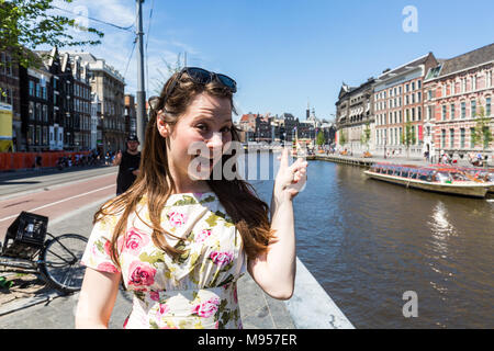 AMSTERDAM, NIEDERLANDE, 27. MAI 2017: Blick auf ein Mädchen am Rokin Promenade und Kanal am 27. Mai 2017. Amsterdam ist beliebt bei Touristen für Hi Stockfoto