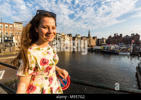 Anzeigen eines touristischen Mädchen am Sonnenuntergang an der Damrak Square in Amsterdam Stockfoto