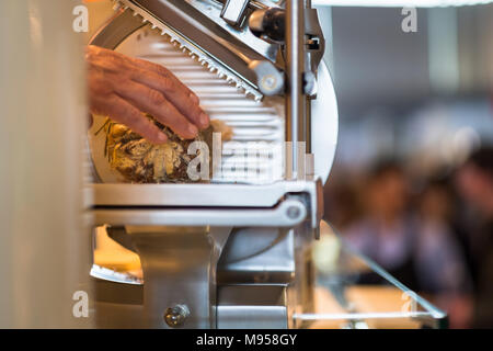 Hand der Metzger schneiden Salami in einem Hobel, um sie zu verkaufen. Stockfoto