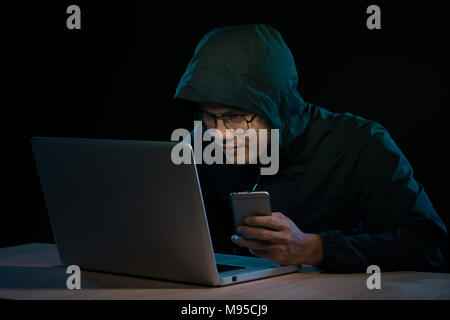 Hooded Cyberkriminalität Hacker mit Handy Internet hacking in Cyberspace, Stockfoto