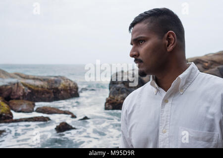 Smart aussehenden asiatischer Mann in der Nähe von der Küste zur Seite. Er ist aus Sri Lanka. Stockfoto