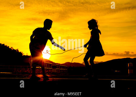 Silhouette, glückliche Kinder Tauziehen spielen von Krieg auf Wiese, Sonnenuntergang, Stockfoto