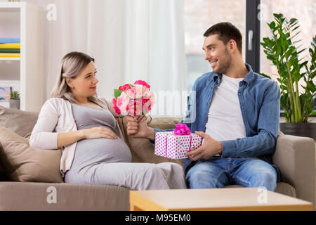 Mann Blumen zu schwangere Frau zu Hause Stockfoto