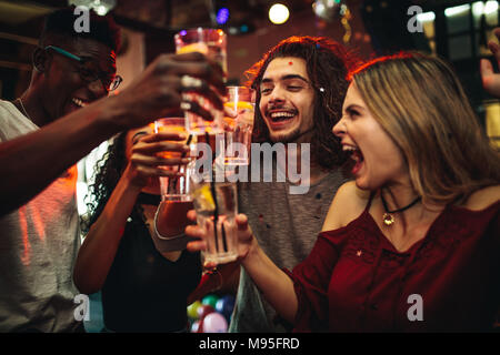 Junge Männer und Frauen eine Party feiern, trinken und tanzen. Gruppe von Freund toasten Getränke und Spaß im Nachtclub. Stockfoto